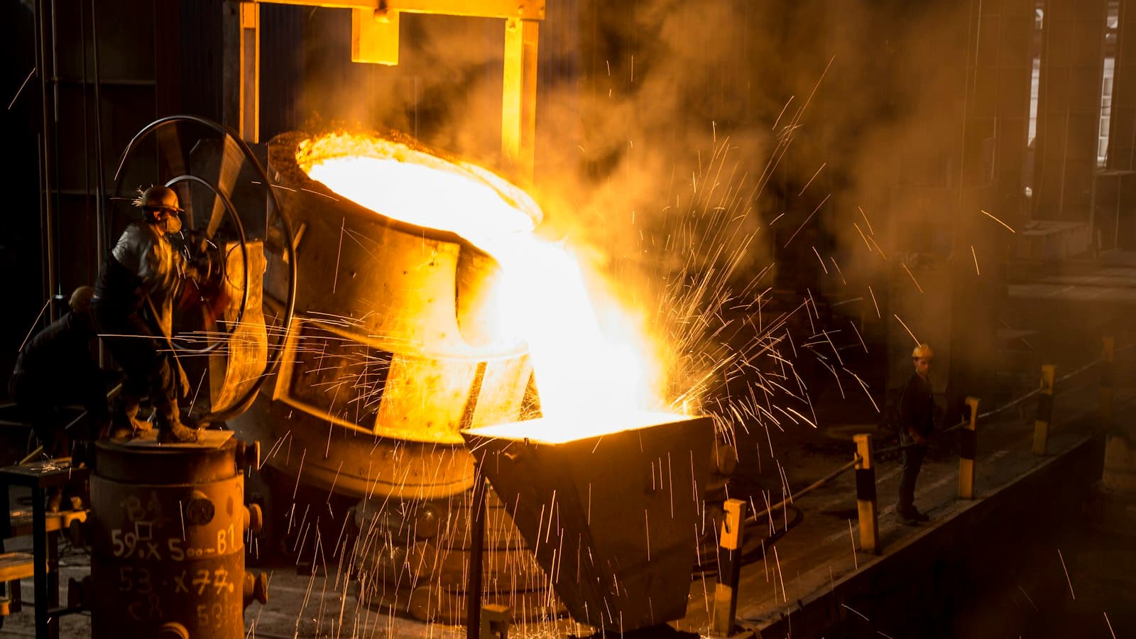 Molten steel pouring from a ladle in a steel mill, sparks flying around the workers
